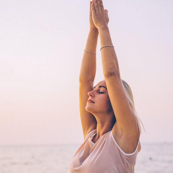 Person meditating peacefully outdoors during sunrise.